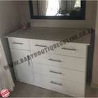 White dresser with multiple drawers and a mirror above it in a room setting.Large Compactum - 3 Top Drawers White B0028