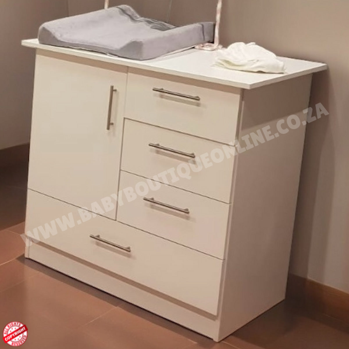 White baby changing table with drawers and a gray cover on a brown floor.