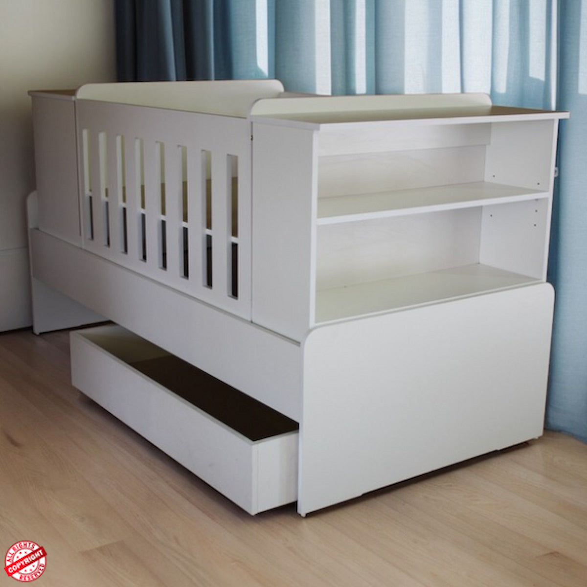 BabyBedroominaBox5-in-1Cot White crib with bookshelves and drawers in a room with blue curtains.