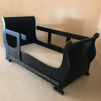 Black toddler bed with 'www.babyboutiqueonline.co.za' branding on a beige background