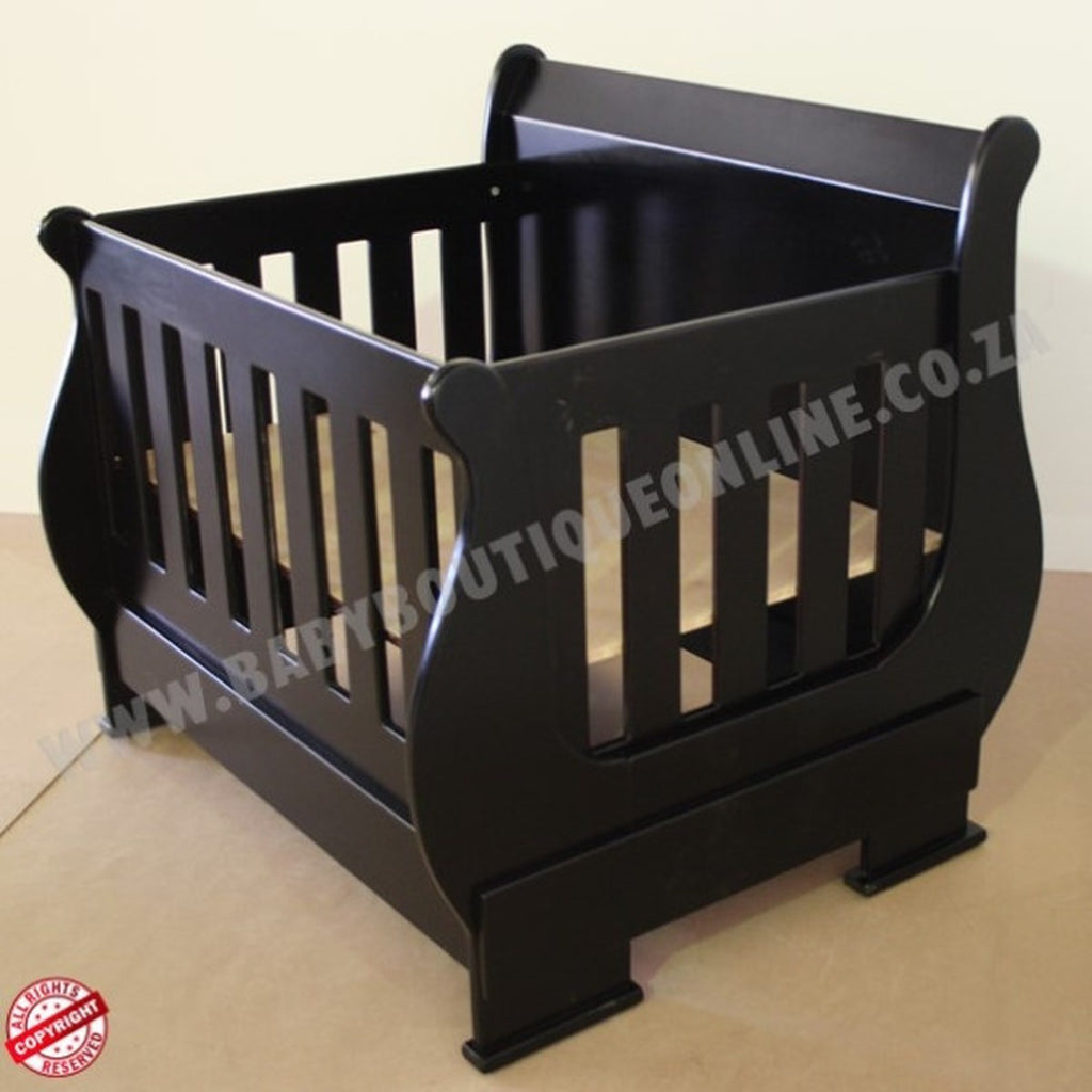SleighCot-Convertsinto3.4Bed Black wooden crib on a beige floor with a plain background