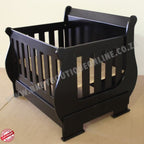 SleighCot-Convertsinto3.4Bed Black wooden crib on a beige floor with a plain background