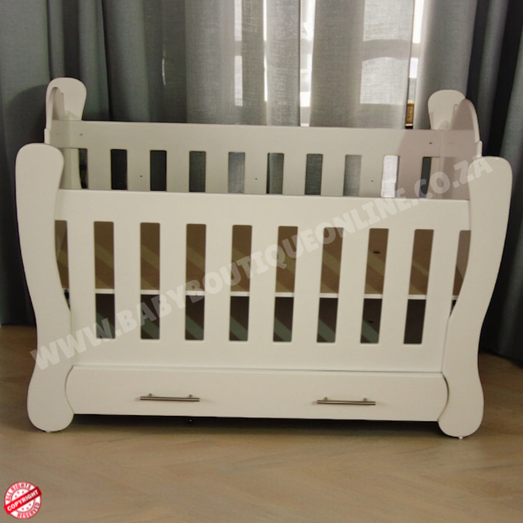 Hurricane Cot White crib with slatted design on a wooden floor with curtains in the background