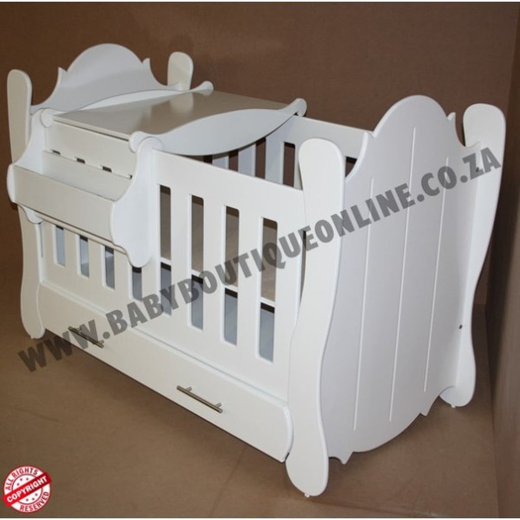 Hurricane Cot White crib with slatted design on a wooden floor with curtains in the background