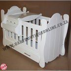 Hurricane Cot White crib with slatted design on a wooden floor with curtains in the background
