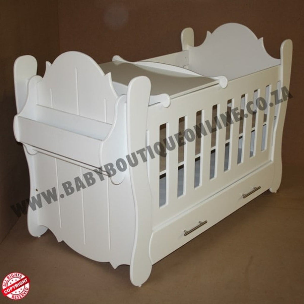 Hurricane Cot White crib with slatted design on a wooden floor with curtains in the background