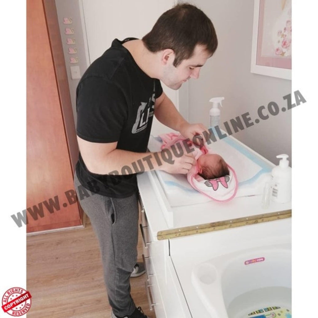 Man holding a baby in a changing table with 'Boutique Online' branding.