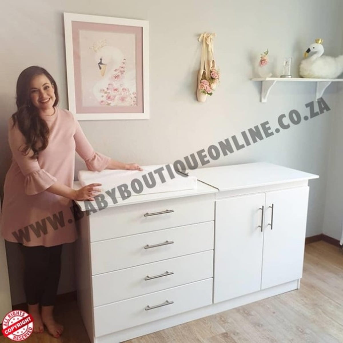 Woman standing next to a white dresser with 'BabyBoutiqueOnline.co.za' branding.