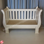 2in1 Sleigh Cot White baby crib with a beige mattress against a gray curtain background
