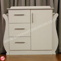 White nursery dresser with drawers and a door against a neutral background