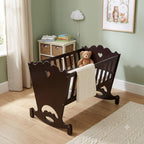 A dark brown wooden baby crib with heart-shaped cutouts on the front, styled in a nursery with a teddy bear inside and a white blanket draped over the side.