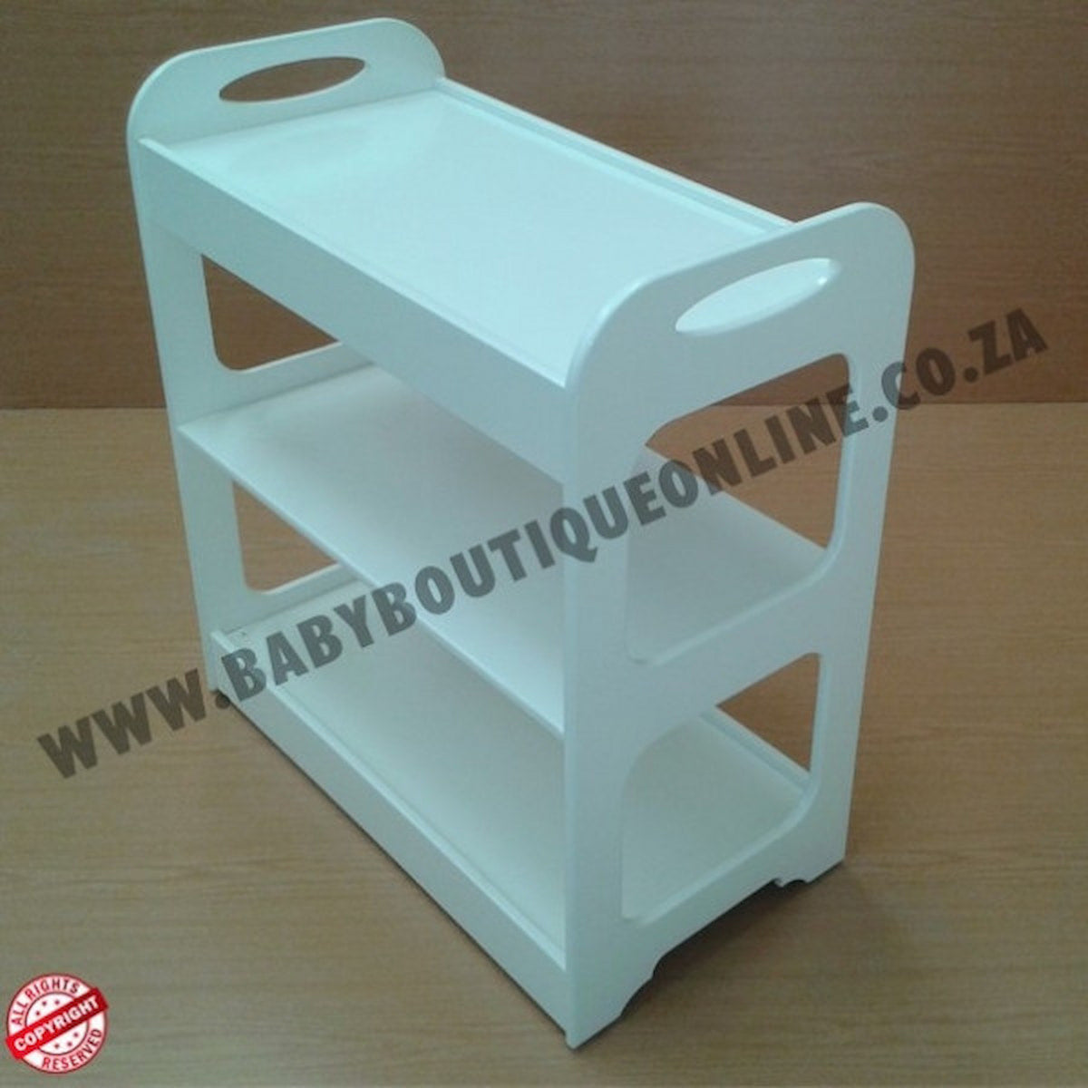 White changing trolley on a wooden surface with 'www.babyboutiqueonline.co.za' branding.