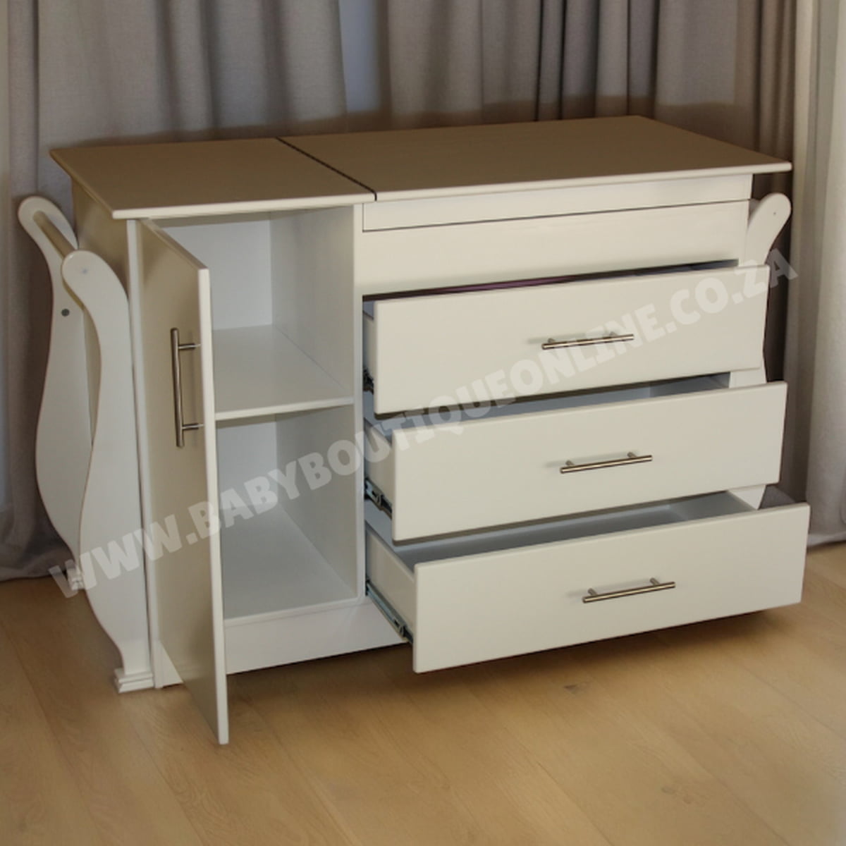 White dresser with open drawer and closed cabinet on a wooden floor.