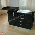 Black baby changing table with a white basin on a wooden floor.