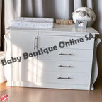 White dresser with baby items on top, including a sheep plush toy and photo frame, with 'Baby Boutique Online SA' branding.