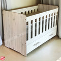 Large Wooden Cot with Split Drawer White with white sides and drawers on a light wooden floor.