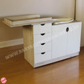 Baby changing table with wooden top and white cabinet on a wooden floor.