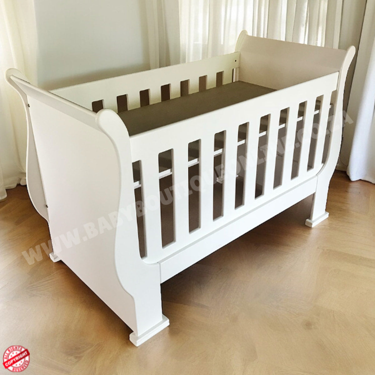 3-in-1 Sleigh Cot and Co-Sleeper White baby crib on a wooden floor with white curtains in the background