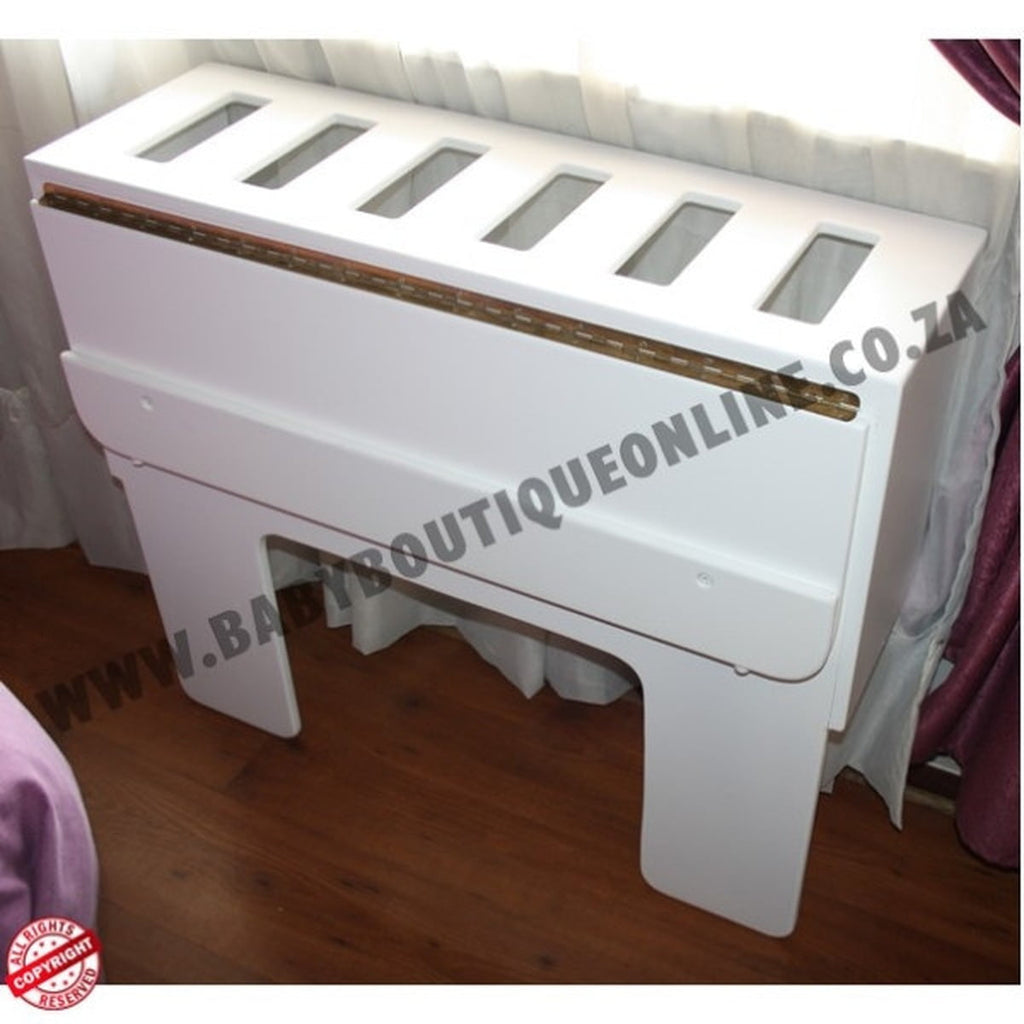 White baby co sleeper with glass panels on a wooden floor.
