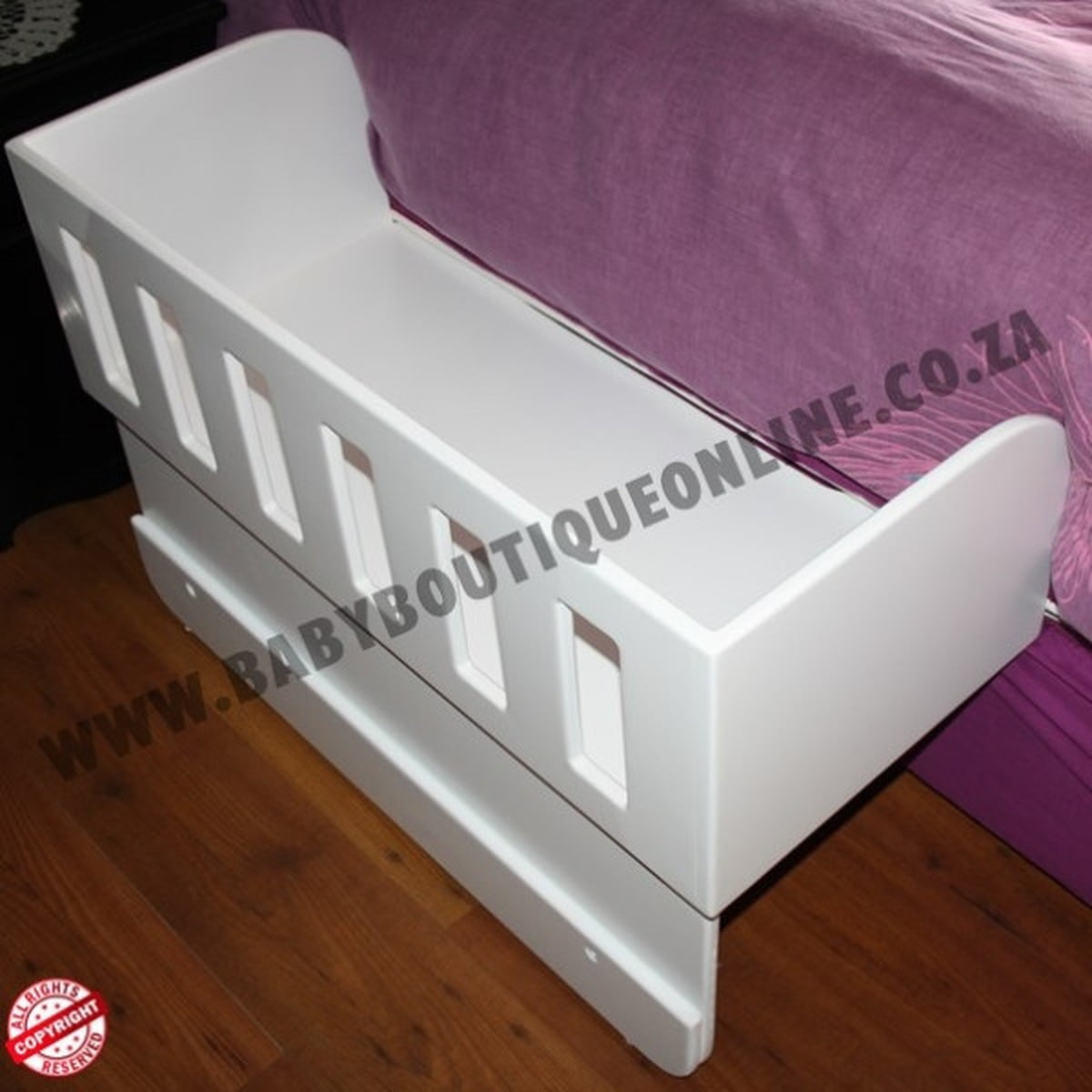White baby co sleeper crib bumper on a bed with visible branding.