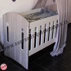 Large Wooden Cot-Round Sides Wooden crib with a canopy in a room setting, featuring a brand logo.