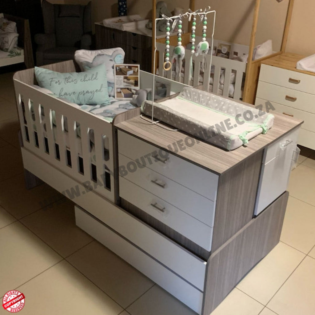 Baby crib with changing table and storage drawers in a room setting.