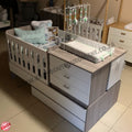 Baby crib with changing table and storage drawers in a room setting.