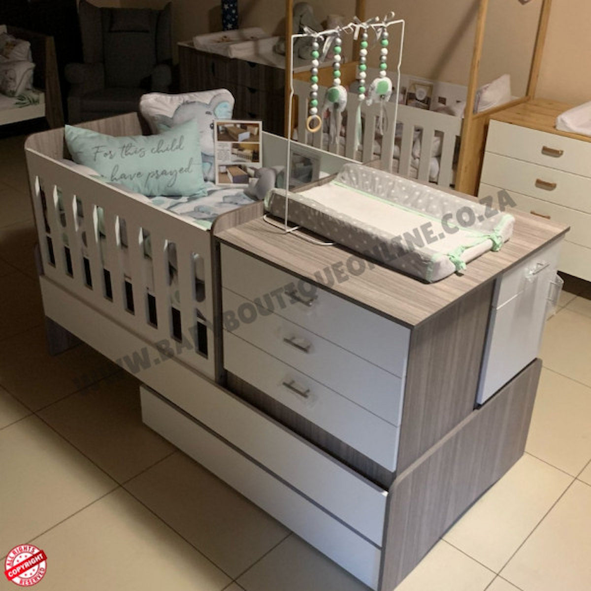 Baby crib with changing table and storage drawers in a room setting.