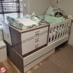 Children's room with a crib, dresser, and toys, featuring 'Baby Boutique' branding.