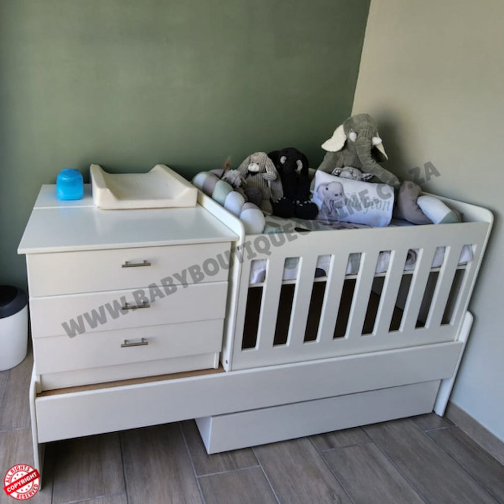 Babybedroominabox5-in-1Cot White crib with toys and a changing table in a nursery setting.