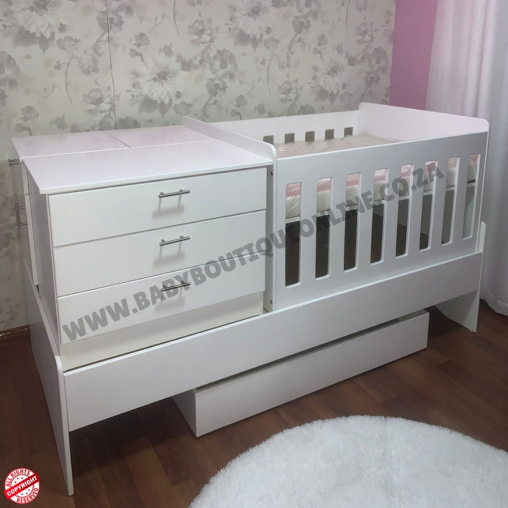 Babybedroominabox5-in-1Cot White baby crib with changing table in a room with floral wallpaper.