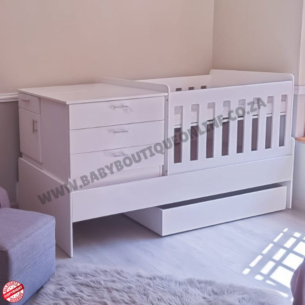 Babybedroominabox5-in-1Cot White crib with drawers in a room setting, featuring the brand 'Baby Boutique'.