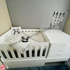 Babybedroominabox5-in-1CotWhite crib with panda-themed bedding and a jewelry stand in the background.