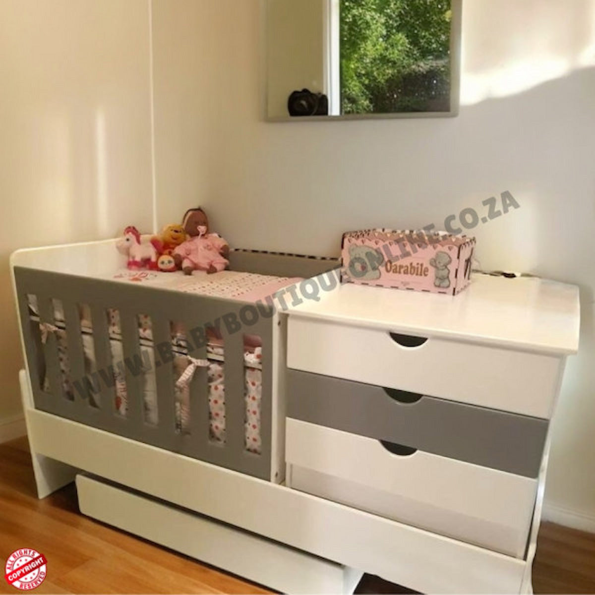 Bedroominabox5-in-1Cot White crib with gray accents and pink bedding in a room.