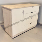 Wooden dresser with multiple drawers on a plain floor and wall.