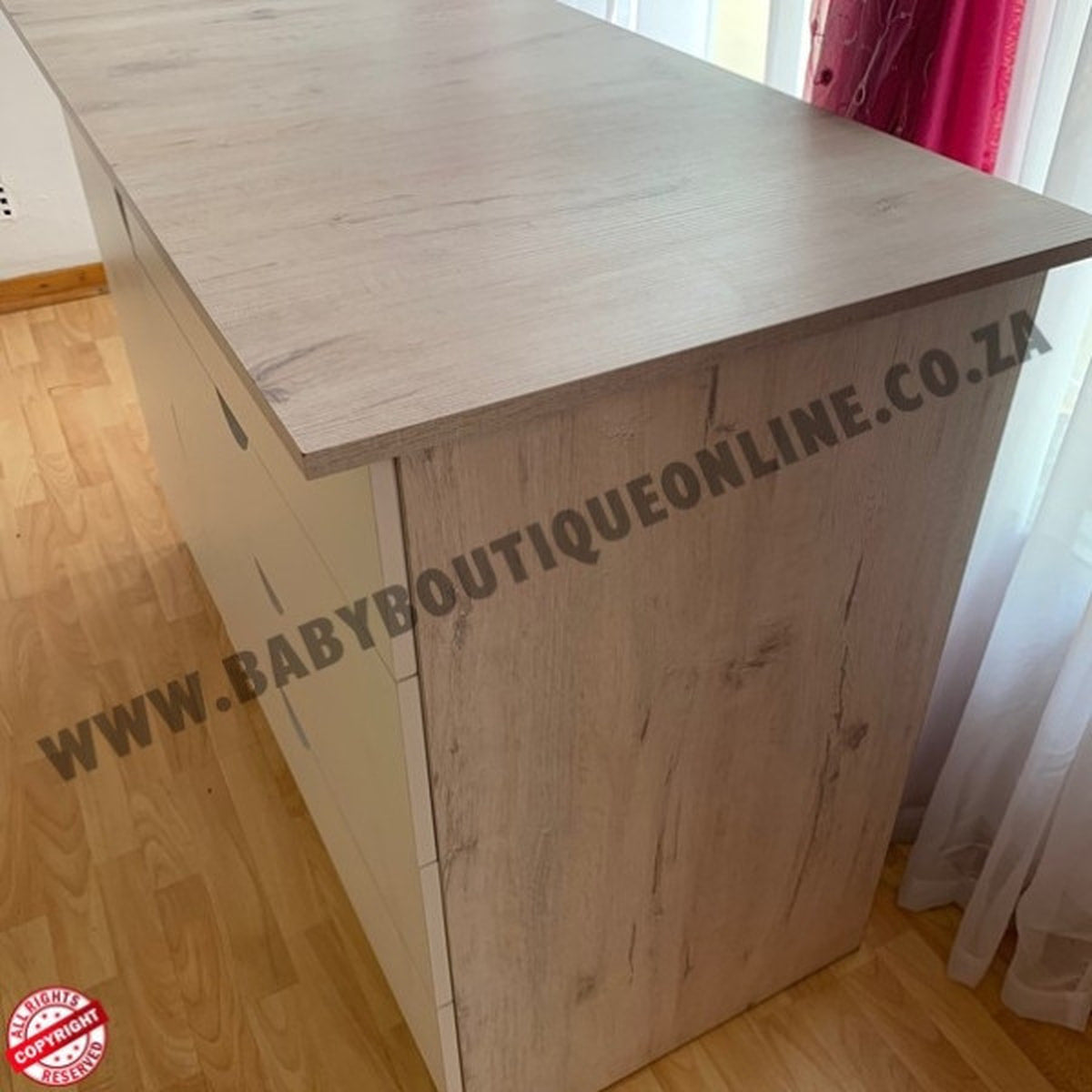 Wooden furniture with 'www.babyboutiqueonline.co.za' branding on a wooden floor.