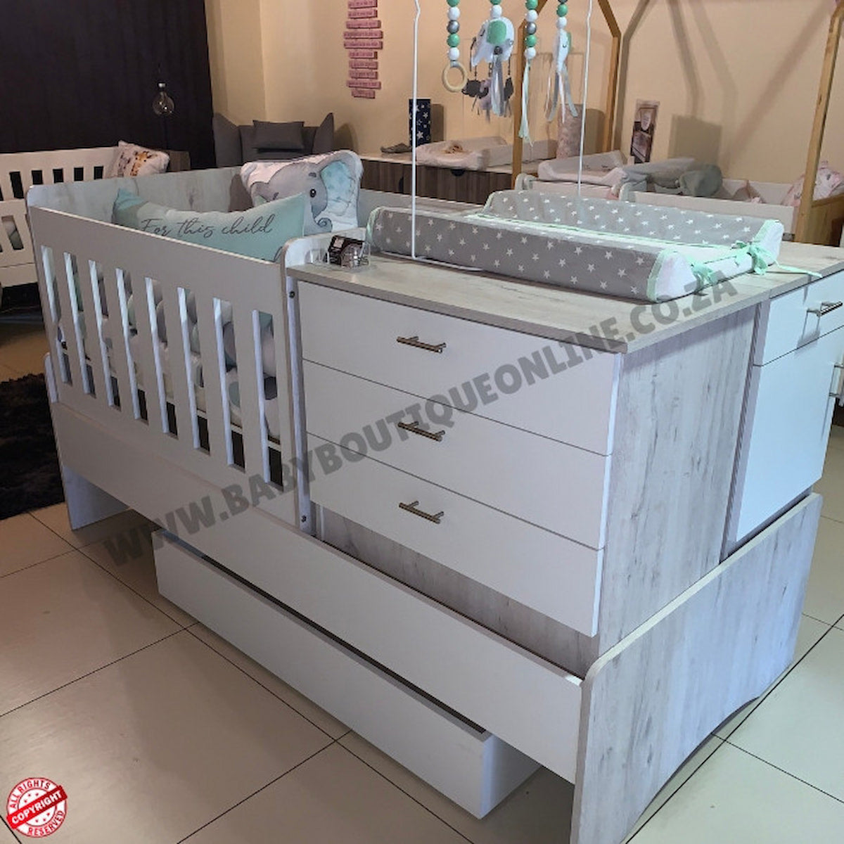 White baby crib with drawers and changing table in a showroom setting.