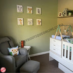 Nursery room with green walls, baby furniture, and decorative elements.