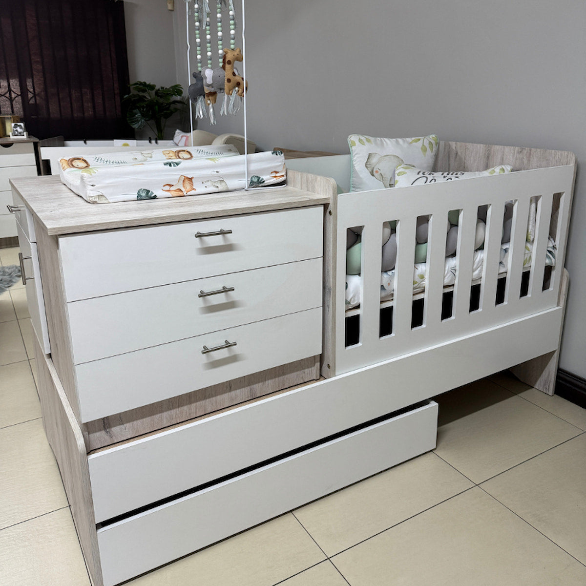 White crib with drawers and baby items in a room setting