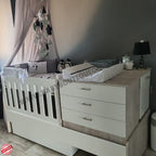 Baby crib with canopy and dresser in a nursery setting