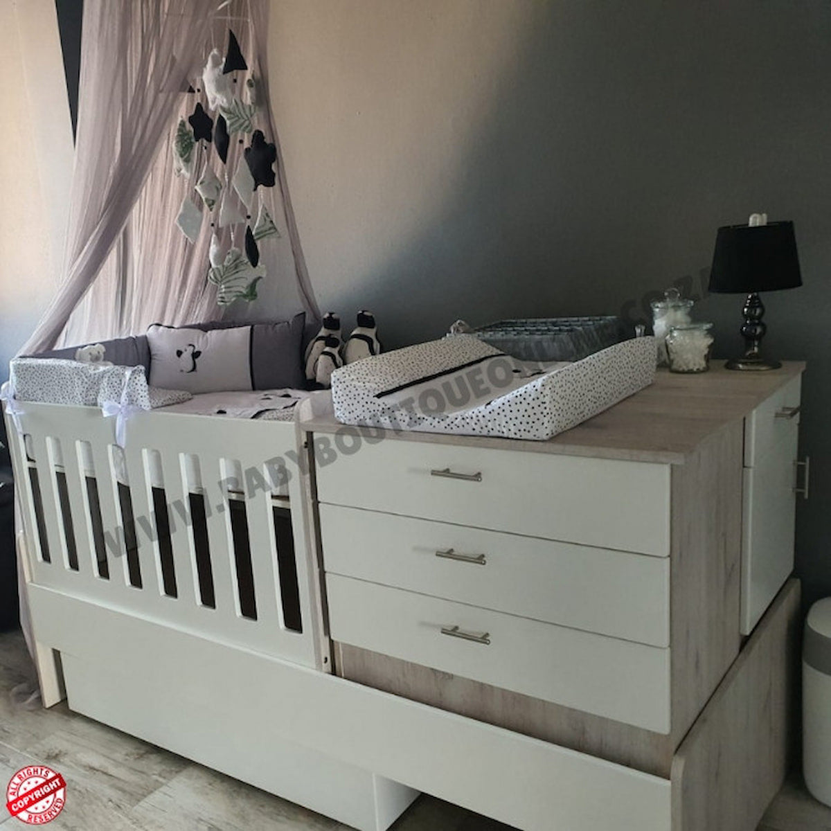 Baby crib with canopy and dresser in a nursery setting