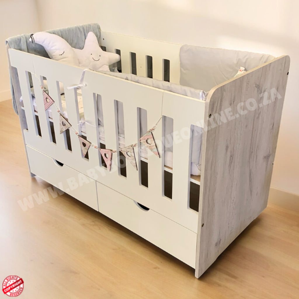 LargeWoodenCotwithSplitDrawerWhite_NordiC with wooden sides and gray bedding on a light wooden floor.