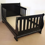 Black toddler bed on a beige floor with a white background