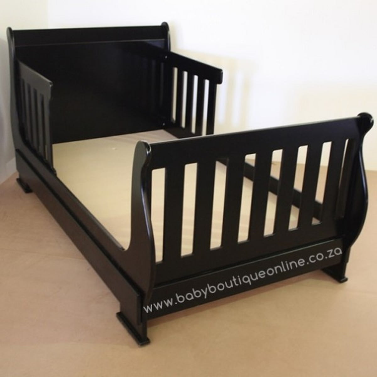 Black toddler bed on a beige floor with a white background