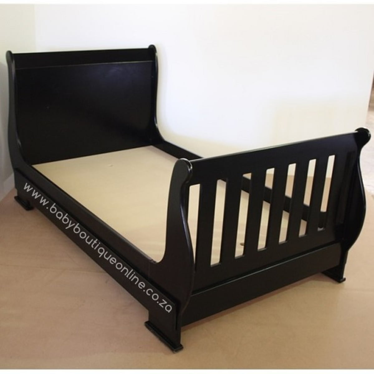 Black toddler bed with beige mattress on a white background