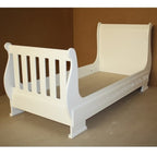 White wooden toddler bed against a brown background
