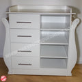 White baby changing table with drawers and shelves on a wooden floor.