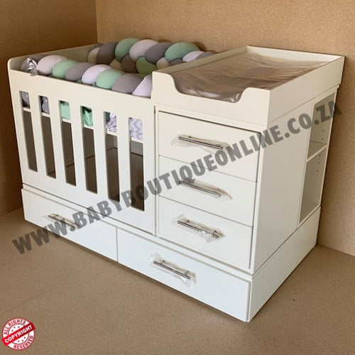 BabyBedroominaBox4-in-1 White baby changing table with drawers and a crib on a brown background