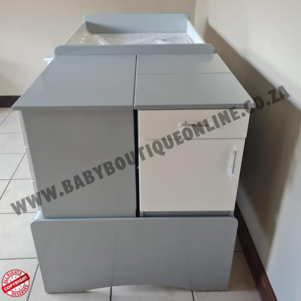 Gray baby changing table with a white top on a tiled floor, branded 'Baby Boutique Online'.BabyBedroominaBox5-in-1Cot