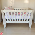 Emma Large Wooden Cot-White_NordicIce White crib with floral bedding on a wooden floor